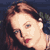 Pixelated static image of a person's face with brown hair and red lips against dark background.