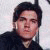 Two side-by-side pixelated portraits of a person with dark hair, one in black clothing against light background, the other in white shirt and cap against darker backdrop.