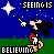 Pixelated Mickey Mouse figure in red shorts and yellow shoes points upward against blue starry background with green horizontal bands, text "SEEING IS" above and "BELIEVING" below.