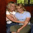 Two figures embrace in a pixelated image; one wears light blue shirt and dark pants, the other has long hair and green clothing.