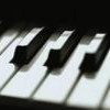Close-up of piano keys with alternating black and white keys, showing partial key surfaces and shadows.