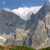 Pixelated landscape with blue sky, white clouds, and gray mountains under bright lighting.
