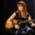 A small image shows a person with long brown hair playing an acoustic guitar, next to stylized text and red phrase fragments on black background.