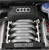 Static pixelated image of a dark vehicle grille with horizontal slats and a circular blue-and-white emblem on the right side.