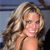 A static pixelated image shows a person with long wavy light brown hair, fair skin, and a neutral expression against a blurred background.