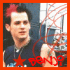 A person with red-tinted hair wears a dark sleeveless shirt and necklace, with red circular lines and a red star in the foreground.