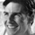 Black-and-white pixelated static icon showing a partial face with dark hair and visible facial features including eyes, nose, mouth, and cheekbones.