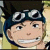 Pixelated anime-style character with spiky black hair, round goggles on forehead, and a slight smile against a blurred background.
