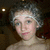 Pixelated close-up of a person with light skin and dark curly hair, wearing a white headband against a dark background.