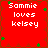 Red background with white text reading "Sammie loves kelsey" and scattered green four-leaf clover shapes.