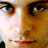 Pixelated close-up of a human face with visible eyes, nose, and mouth in warm brown and beige tones.