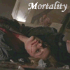 A person with light brown hair lies on a bed, hand near face, in a dimly lit room with a mirror and lamp visible; the word 'Mortality' appears above in white text.