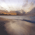 Pixelated landscape with water, distant land, and sky gradient transitioning from light to dark tones.