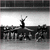Black-and-white pixelated image of a figure with arms raised above head, standing on a platform with large stylized text below.