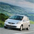 Pixelated static image of a white sedan on a road with greenery and water in the background.