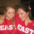 Two people in red hooded sweatshirts with white text, standing close together against a dark background.