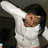 Pixelated image of a person with long dark hair wearing white clothing, raising one arm in a dynamic pose against a muted background.