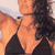 Static pixelated image of a person in a black bikini top against an orange-toned background with blurred shapes.