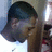 Pixelated image of a person with dark hair wearing a white shirt, head turned slightly left against light background.