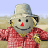 Animated scarecrow in red checkered shirt and blue pants with a gray hat, standing in a field with arms moving from side to side.