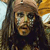 Pixelated static image of a person with long dark hair wearing a brown headband and dark clothing against a blurred background with light and brown tones.