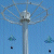 A tall, slender metallic structure with a rounded top and multiple curved arms extends from its center against a blue background.