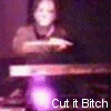 A person in a brown top performs hand movements over a keyboard with purple lighting, text "Cut it Bitch" visible below.