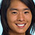 Pixelated close-up of a smiling person with dark hair, light skin, and visible teeth, set against a blurred background.