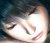Pixelated close-up of a person's face with closed eyes, light skin tone, and visible eyelashes against dark background.