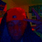 Pixelated red and blue figure with a single visible eye, wearing dark clothing against a blurred background.
