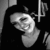 Pixelated grayscale image of a stylized face with closed eyes and a broad smile, set against dark background elements.