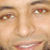 Pixelated close-up of a human face showing eyes, nose, mouth, and eyebrows with visible teeth in a smile.