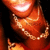 A close-up of a smiling person with dark hair wearing a gold chain necklace, showing subtle animation changes in the mouth and necklace.
