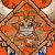Pixelated cartoon character with blue helmet and orange armor, holding a sword, with a diamond-shaped emblem featuring a star and horns on an orange background.