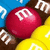 A pixelated red sphere with white text sits among blue, brown, and yellow shapes. White question marks appear on the left and right edges of the image.