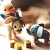 A static image shows a wooden horse with a green bridle, a small elephant with gray body and white ears, and three yellow blocks with black symbols on a light brown surface.