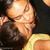 Two people in close embrace, one wearing a black top and the other yellow, with visible skin tones and dark hair.
