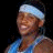 Pixelated image of a person wearing a light blue headband and sleeveless shirt with visible shoulder straps, positioned next to repeated text "Melo Melo" in stylized lettering.