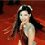A pixelated figure with long dark hair wears a light-colored sleeveless top against a red background with dark accents.