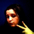 Pixelated image of a person with dark hair and light skin making a peace sign gesture against a dark blue background.