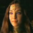 Pixelated static image of a person with long brown hair against dark background, face illuminated by warm light.