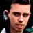 Pixelated static image of a person's face with visible ear, dark hair, and partial clothing against black background.