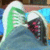 Pixelated static image shows a green and white curved shape with pink accents on dark background, blue and brown tones in surrounding area.