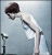 Pixelated figure in white outfit with dark hair, leaning forward against light blue background holding black object.