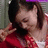 Pixelated static image of a person with dark hair wearing red clothing, set against a muted background.