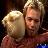 Two figures in close embrace, one with light hair holding the other against a dark background.