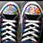 Two black sneakers with white laces and multicolored toe caps, surrounded by small heart shapes on a gray background.