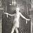 A pixelated grayscale image shows a figure with outstretched arms against a dark background with vertical elements.