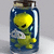 A pixelated yellow alien-like figure with black eyes and a green body is encased in a blue glass jar with a brown cork top.