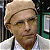 Pixelated close-up of a person wearing a light brown turban and white shirt, with a green and dark background.